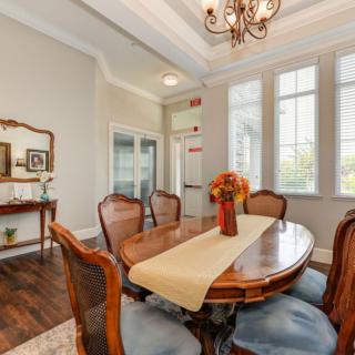 A traditional dining room with a wooden table, elegant chairs, and a chandelier.