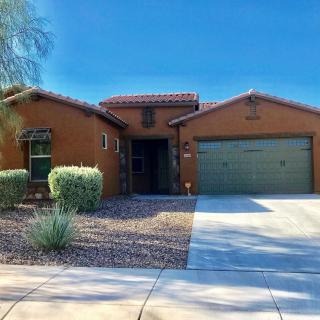A southwestern-style house with a two-car garage and desert landscaping on a sunny day.