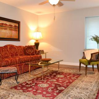 A cozy living room with a patterned sofa, glass coffee table, and elegant lighting.