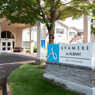 Entrance to Avamere at Albany with a sign and driveway surrounded by trees.