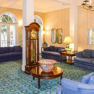 A cozy lobby area featuring blue sofas, a grandfather clock, and elegant decor.