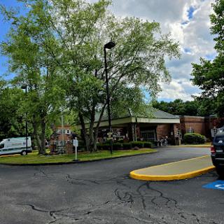 A welcoming entrance to a building surrounded by greenery under a cloudy sky.