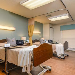 A well-lit and organized hospital patient room with two beds and medical equipment.