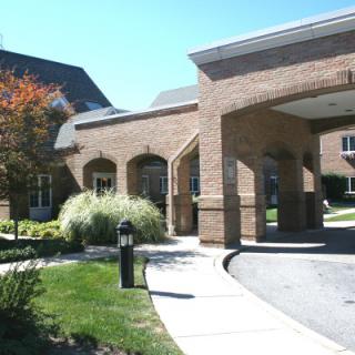 A brick building with a covered entrance and landscaped surroundings.