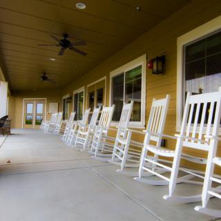 A row of white rocking chairs on a spacious porch.