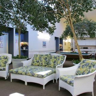 A cozy indoor seating area with white wicker furniture and decorative green plants, creating a relaxing atmosphere.