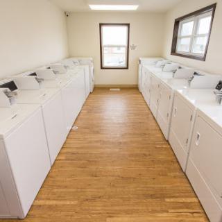 A spacious and well-lit laundry room featuring several washing machines.