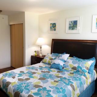 A cozy bedroom with floral bedspread and artwork on the walls.