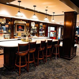 A stylish bar interior with a sleek counter and wooden seating.