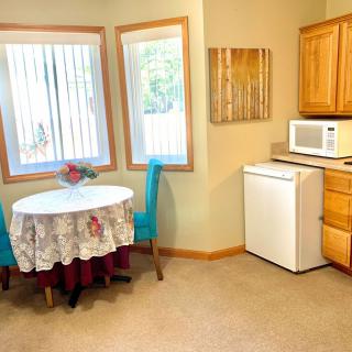 A cozy kitchen corner with a small dining table, chairs, and basic appliances.