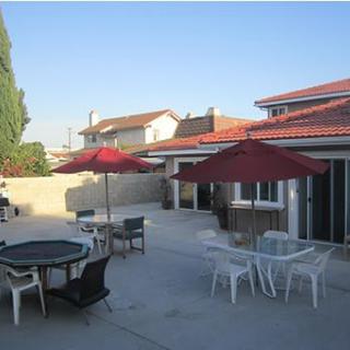 A spacious patio area with tables, chairs, and umbrellas in a residential backyard.