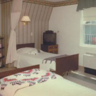 A cozy vintage bedroom with two beds and a classic television.