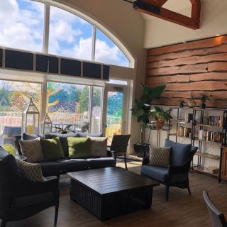 A modern living room with large windows, natural light, and stylish wooden accents.