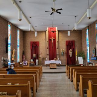 Interior view of a church with an altar at the front and wooden pews for congregants.