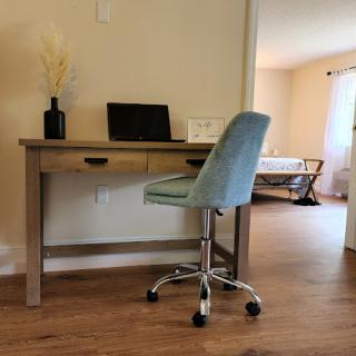 A modern workspace featuring a wooden desk with a stylish chair, set in a cozy room.