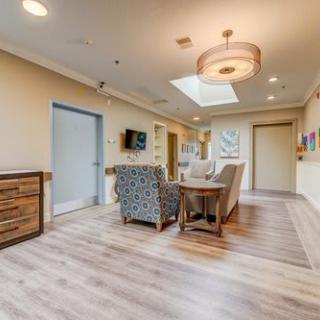 A modern living room with comfortable seating, wooden flooring, and a skylight.