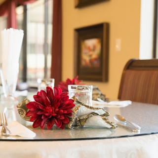 A beautifully arranged dining table featuring red flowers and elegant glassware.