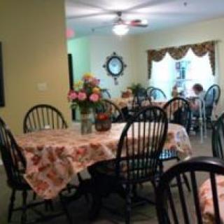 A cozy dining area with tables covered in floral tablecloths and chairs arranged neatly.