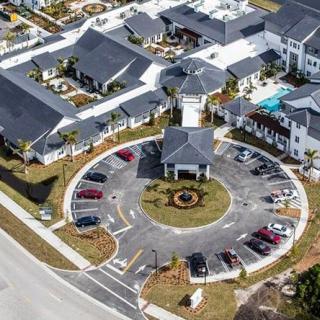 Aerial view of a building complex with a circular driveway and surrounding parking lot.
