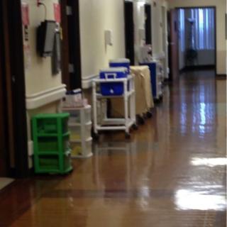 A hospital hallway with medical carts and equipment lined up.