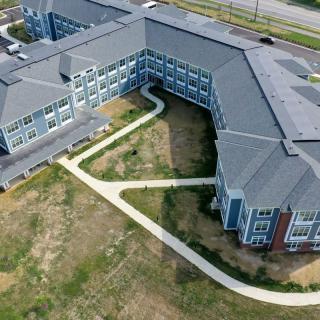 Aerial view of a large building complex with multiple pathways and surrounding green areas.