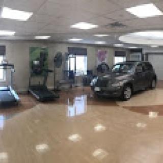 A unique gym setup featuring exercise equipment alongside a parked car.