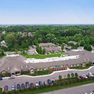 Aerial view of a suburban residential area with buildings, parking spaces, and surrounding greenery.