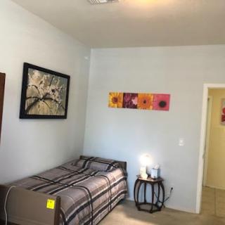 A cozy and well-decorated bedroom featuring a single bed, artwork on the walls, and a nightstand.