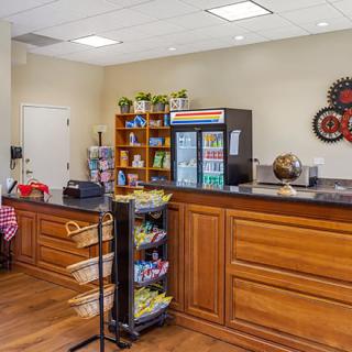 A cozy reception area featuring a snack counter with a vending machine, wooden cabinets, and a merchandise display stand.