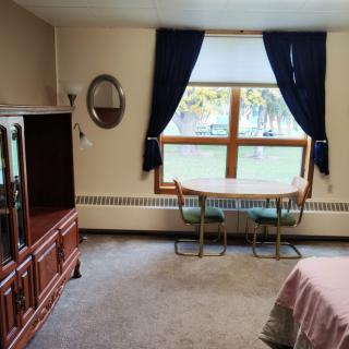 A cozy living room with a table and chairs by the window, complemented by dark curtains.