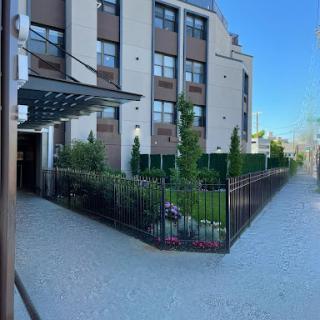 A modern residential building with landscaped surroundings and a fenced entrance.