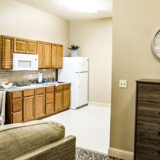A modern kitchen in an apartment with wooden cabinets, a white refrigerator, and a microwave.