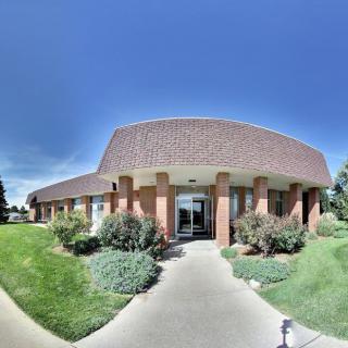 A commercial building with a brick facade and well-maintained landscaping on a sunny day.