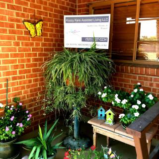 A cozy garden nook featuring a variety of potted plants, vibrant flowers, and charming decorations against a brick wall backdrop.