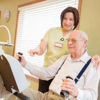A nurse assists an elderly man during an exercise session in a healthcare facility.