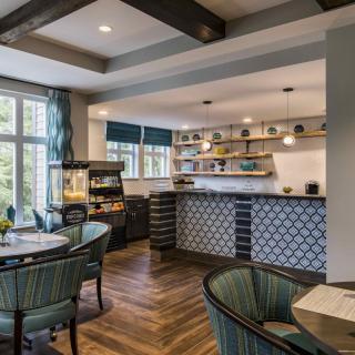 A modern and cozy kitchen with an open dining area, featuring ample natural light, wooden flooring, and stylish decor.
