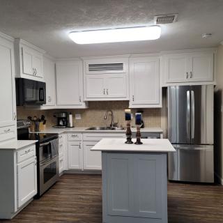 A modern kitchen with white cabinetry, stainless steel appliances, and a central island.