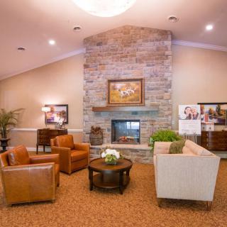 A cozy living room with a stone fireplace, leather armchairs, and a comfortable sofa.