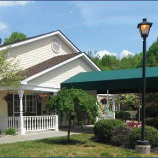 A quaint house with a green awning and surrounding garden.