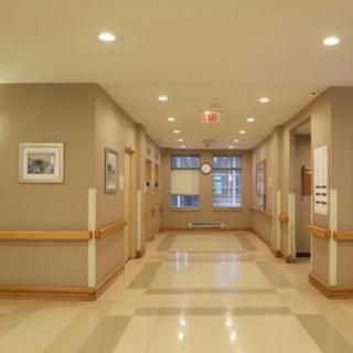 A clean and well-lit hospital corridor with padded railings and framed pictures on the walls.