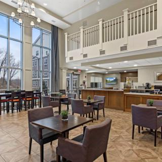 A modern cafe with a spacious dining area featuring high ceilings, large windows, and contemporary seating arrangements.