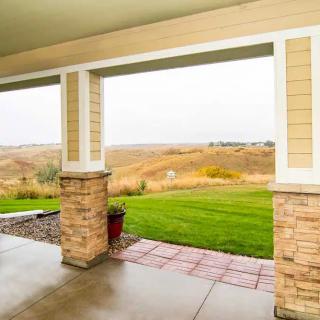 A covered patio overlooking a grassy landscape.