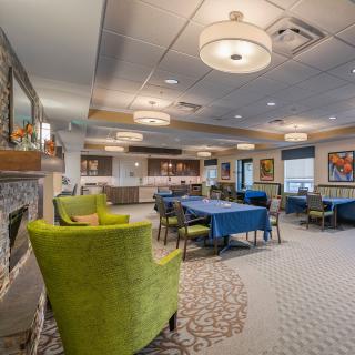 A modern lounge area with bright green chairs and elegantly set tables, showcasing stylish lighting and decor.