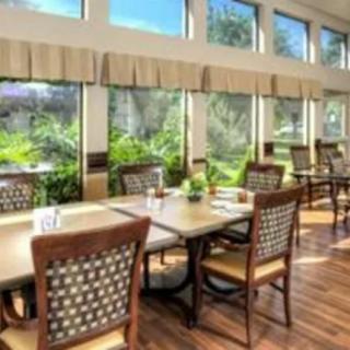A well-lit dining area with large windows and neatly arranged tables and chairs.
