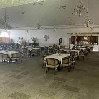 An empty restaurant interior with tables, chairs, and chandeliers.