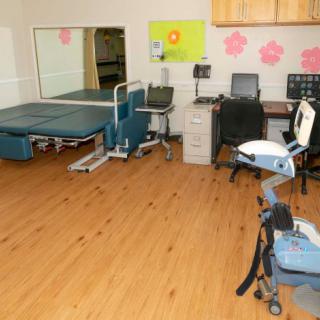 A physical therapy clinic room with exercise equipment and treatment beds.