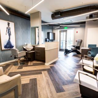 A modern salon interior featuring stylish chairs, artwork on the walls, and wood flooring.