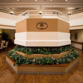 Hotel lobby area with decorative plants and a central structure featuring the hotel's logo.