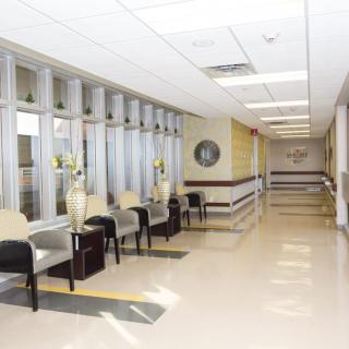 A bright hospital hallway with a waiting area featuring chairs and decorative elements.