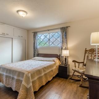 Cozy bedroom with a bed, rocking chair, and window letting in natural light.